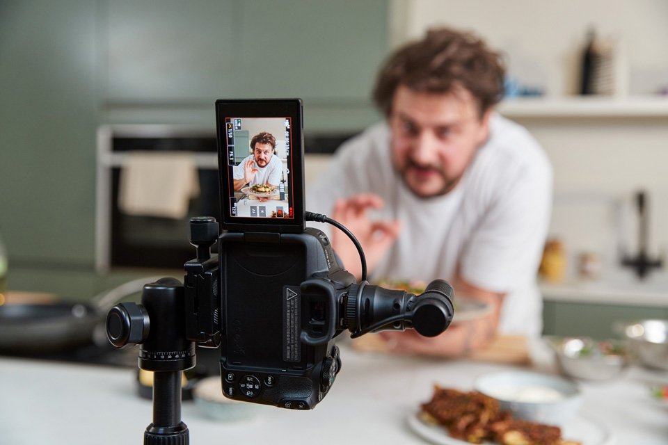 A man shooting a cooking video with Canon EOS R50 do-it-all creator kit.
